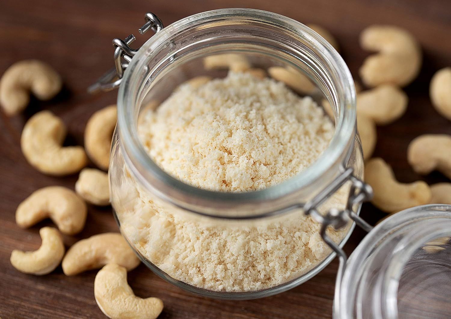 Shows the product (cashew flour or ground cashews) in an attractive, natural setting with whole cashews to communicate freshness and quality in a real-world kitchen context.