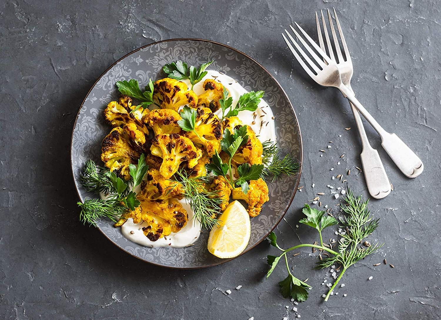 Showcases the product (likely roasted cauliflower or similar food item) in an appetizing, real-world dining context to help shoppers visualize the final result and appeal.