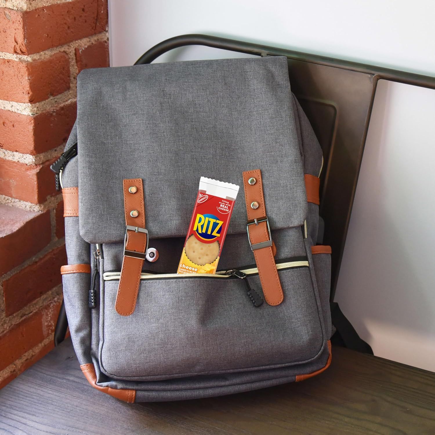 Demonstrates the backpack's compact, portable size by showing it can fit a standard Ritz cracker box, helping shoppers understand its real-world dimensions and capacity.