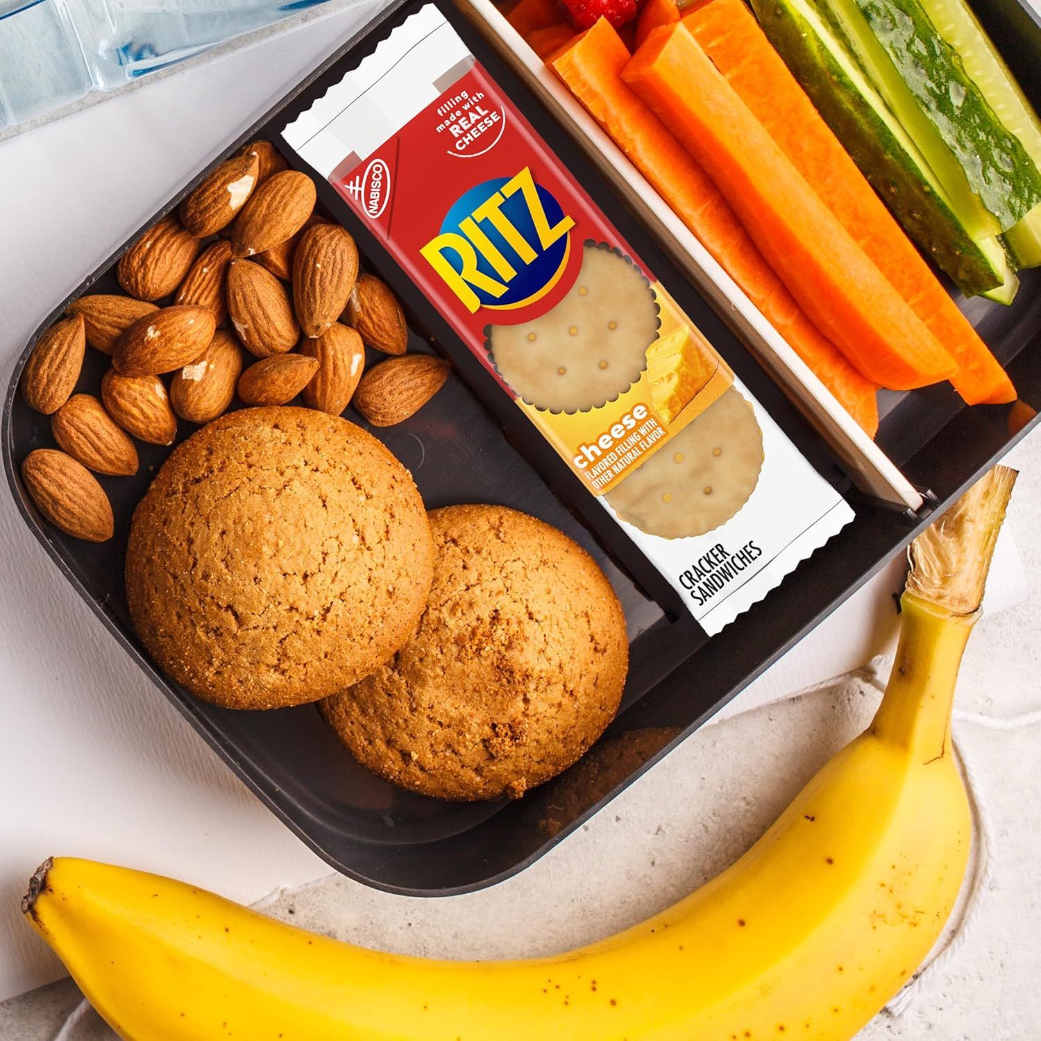 Shows the complete snack kit contents including crackers, almonds, cookies, and fresh vegetables to demonstrate the variety and value of what's included in the package.