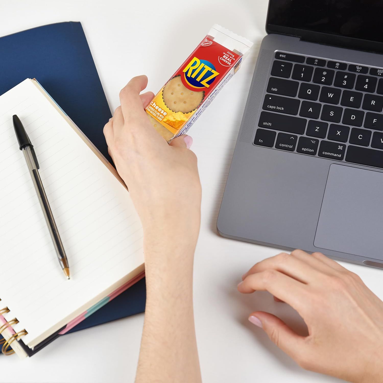 Demonstrates the product in a real-world office or work-from-home context, showing how Ritz crackers fit naturally into a busy workday as a convenient snack option.