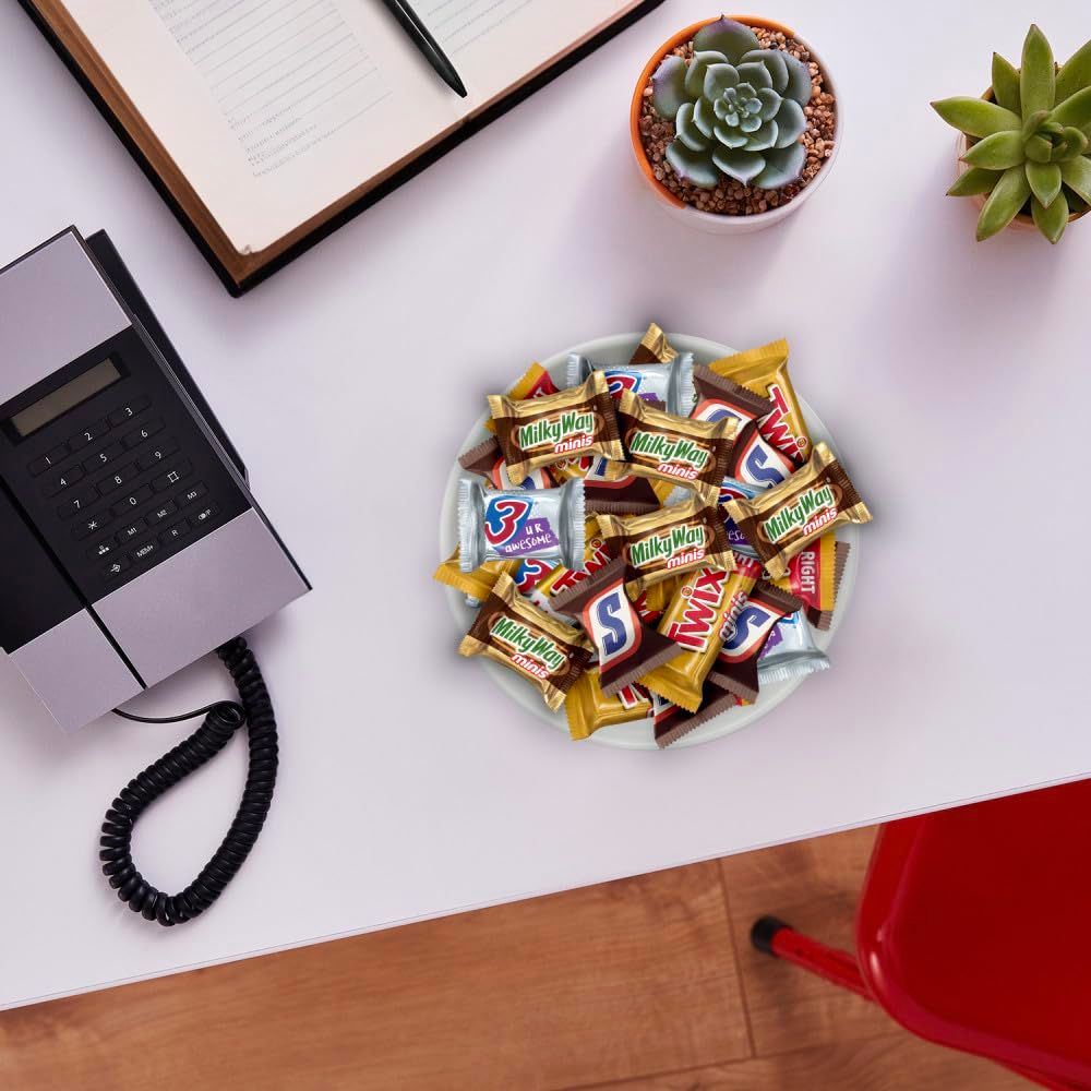 Demonstrates the product in a real-world office environment to help shoppers visualize the candy assortment as a workplace snack option or desk accessory.