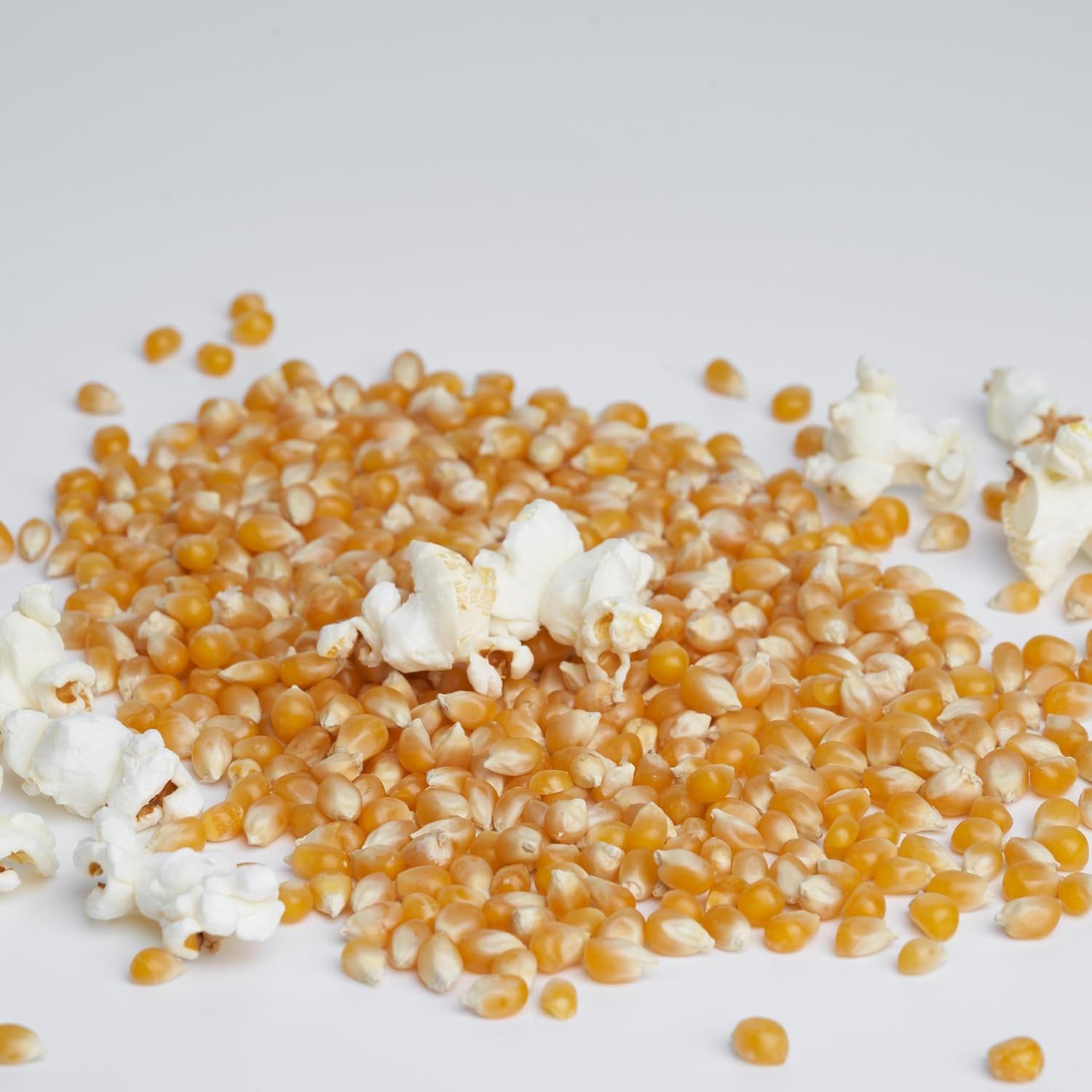 Demonstrates the product's transformation capability, showing unpopped kernels alongside fully popped popcorn to illustrate the end result and quality of the popping process.