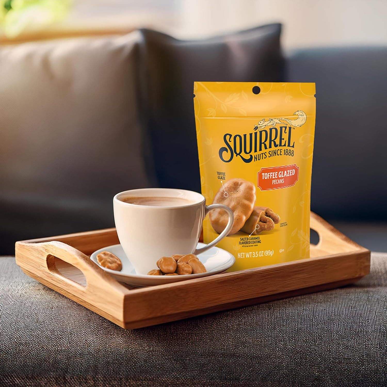 Showcases the product in a cozy, real-world home environment to help shoppers visualize enjoying the toffee glazed pecans as a snack with coffee or tea.
