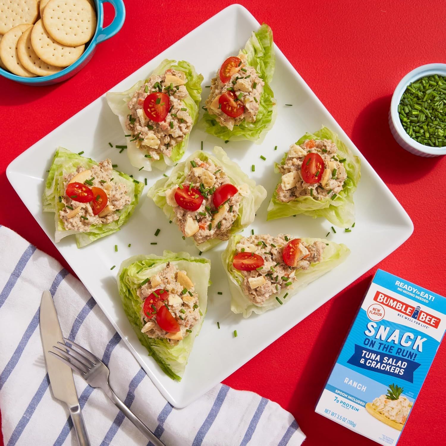 Demonstrates a creative way to use the tuna salad product by showing it served on lettuce cups with tomatoes and crackers, inspiring shoppers with a ready-to-eat meal idea.