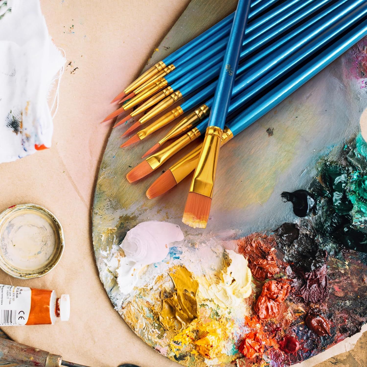 Showcases the product (paint brushes) in an authentic artistic setting to help shoppers visualize the product in real-world creative use.