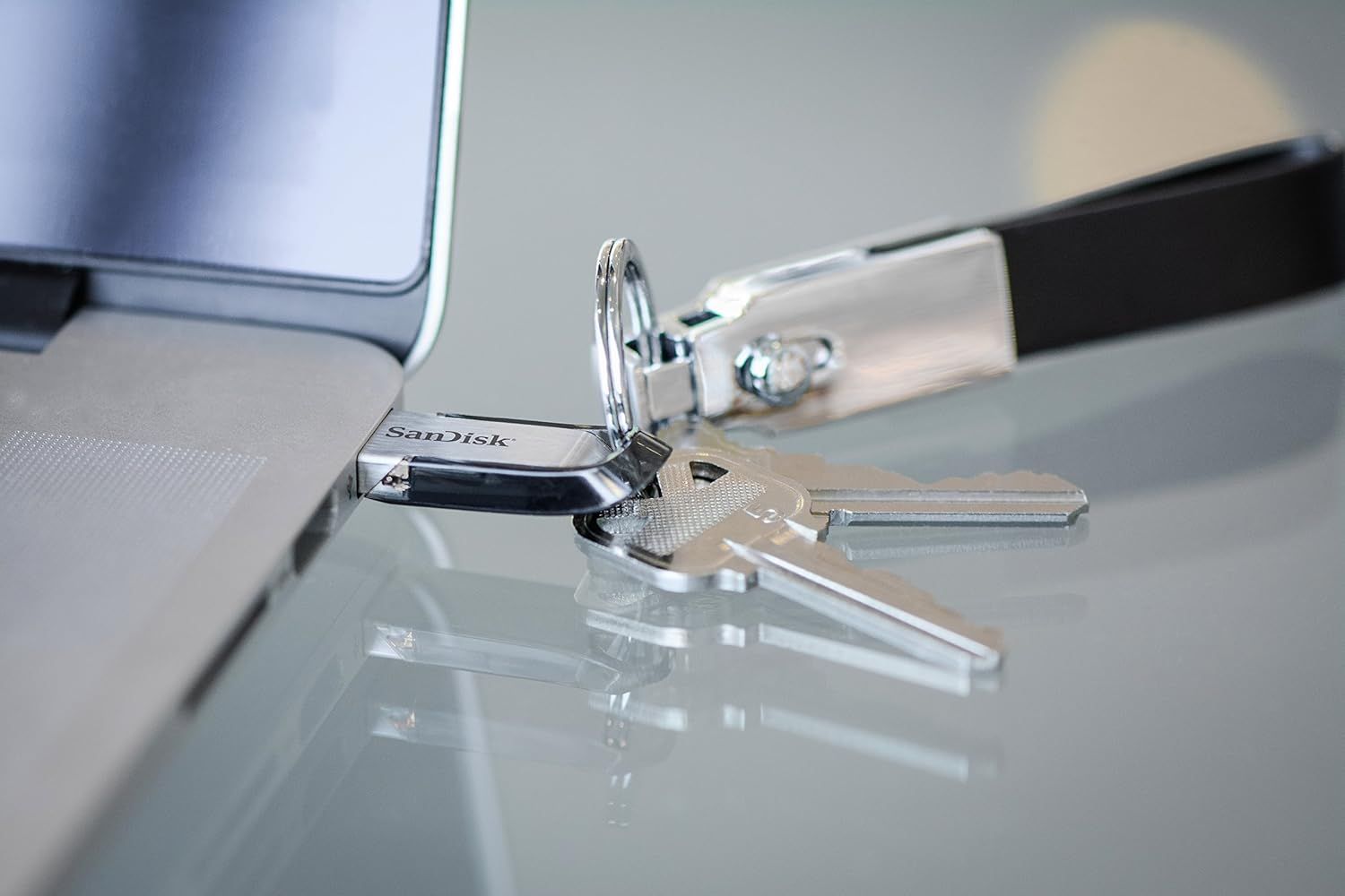Displays the SanDisk USB drive in a clean, real-world lifestyle context with keys to show its compact, portable nature and everyday use case.