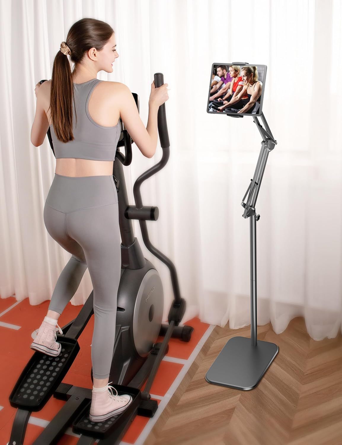 Demonstrates the product in a real-world home fitness setting, showing how the tablet stand enables hands-free viewing during exercise workouts.