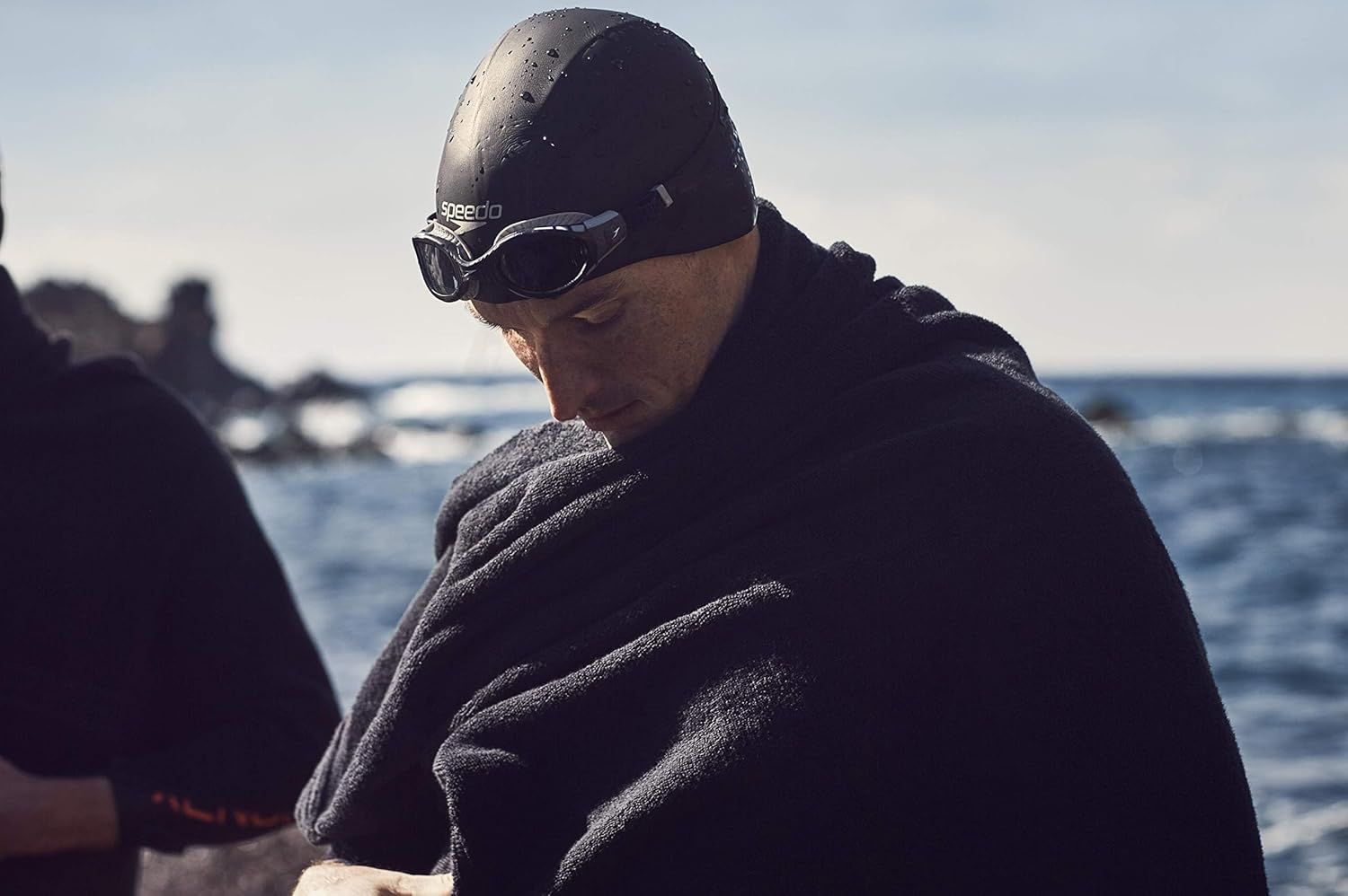 Demonstrates the product in an authentic outdoor swimming scenario to help shoppers visualize themselves using the swim cap and goggles in real conditions.