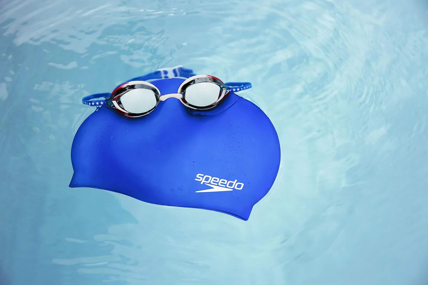 Displays the Speedo swim cap and goggles in a clean, catalog-style photo to show the product clearly without distractions.