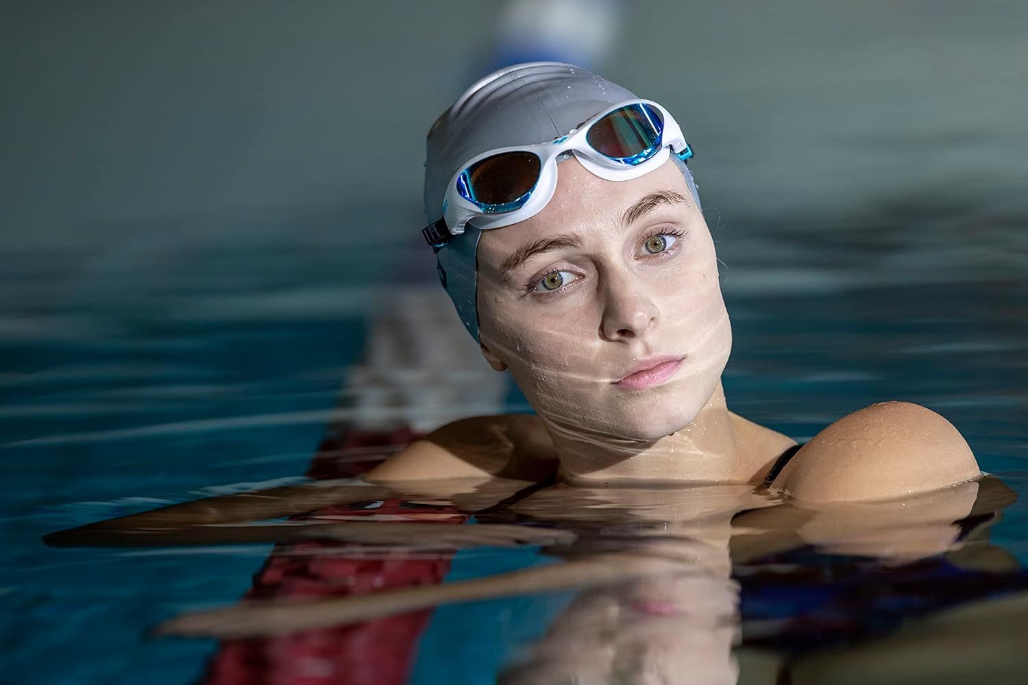 Shows the swim goggles and cap being used in a real swimming pool environment to help shoppers visualize the product in action.