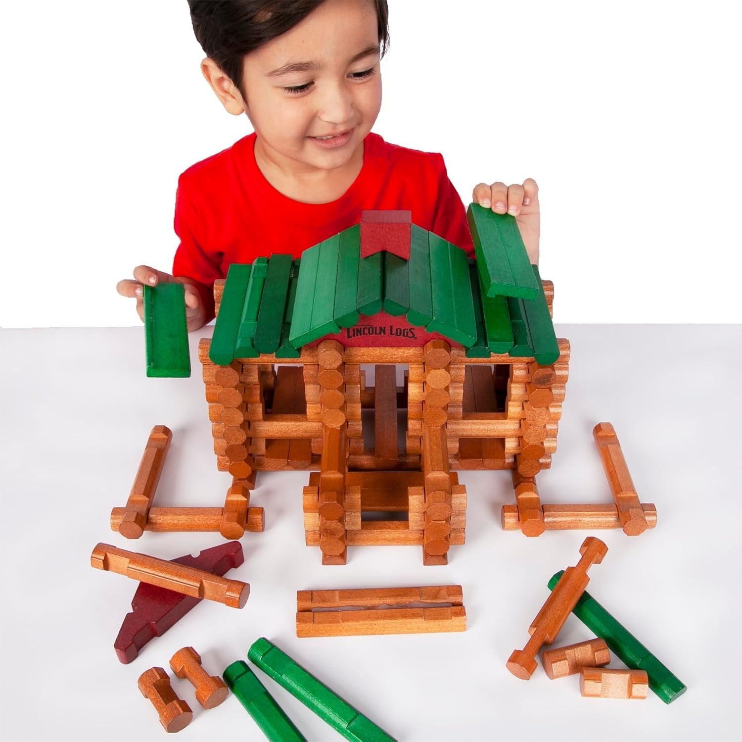 Shows the product in use by a child in a real-world context to help shoppers visualize how their child might engage with and enjoy the Lincoln Logs building set.