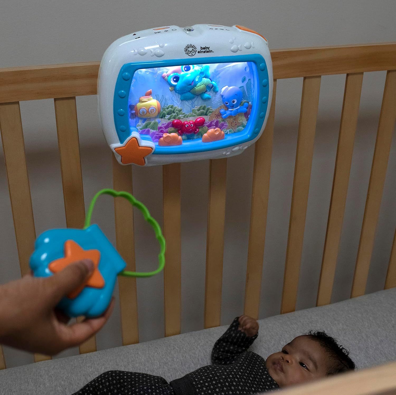 Demonstrates the product's remote control functionality and interactive entertainment features to show parents how the crib toy can be operated from a distance to soothe and engage the baby.