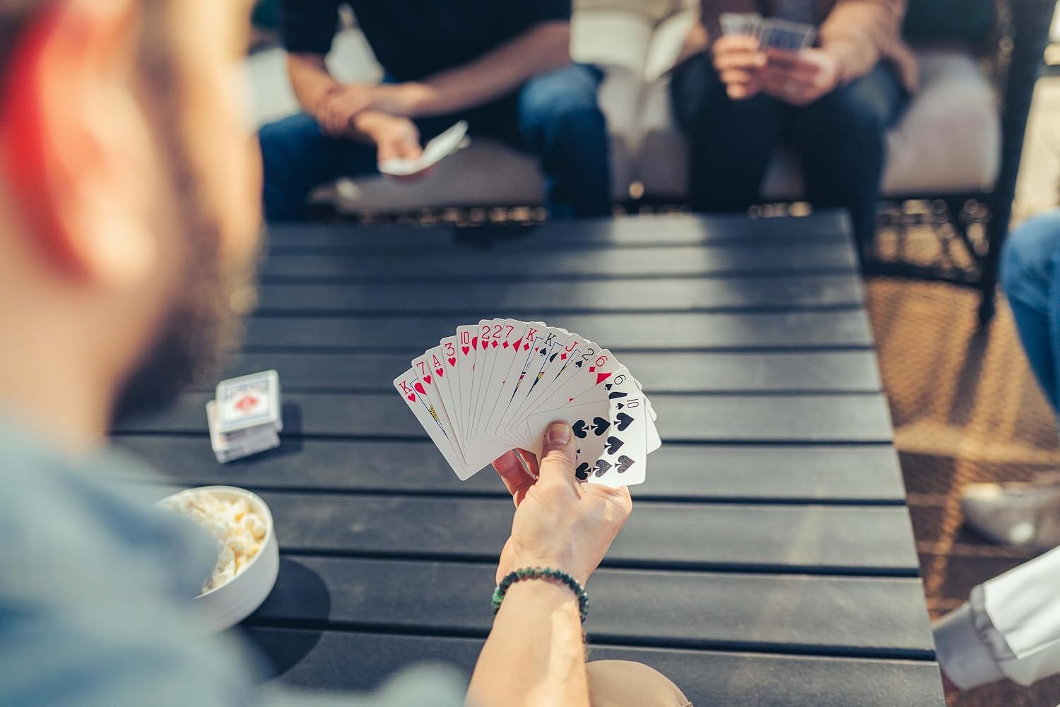 Demonstrates the product (playing cards) being used in a real-world social setting to show its role in bringing people together for entertainment and leisure.