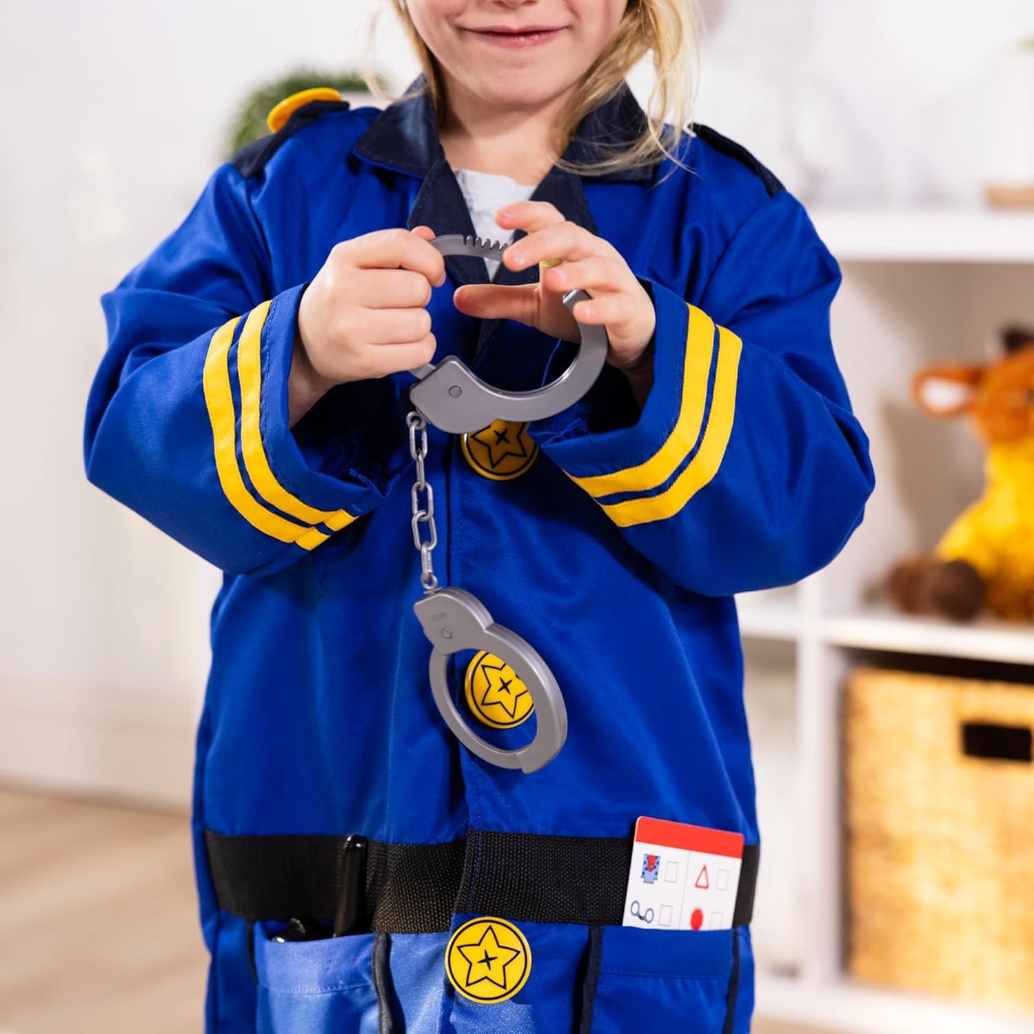 Shows the child wearing the complete police officer costume set with included accessories like handcuffs, badge, and ID card to demonstrate what comes in the package and how it looks when worn.