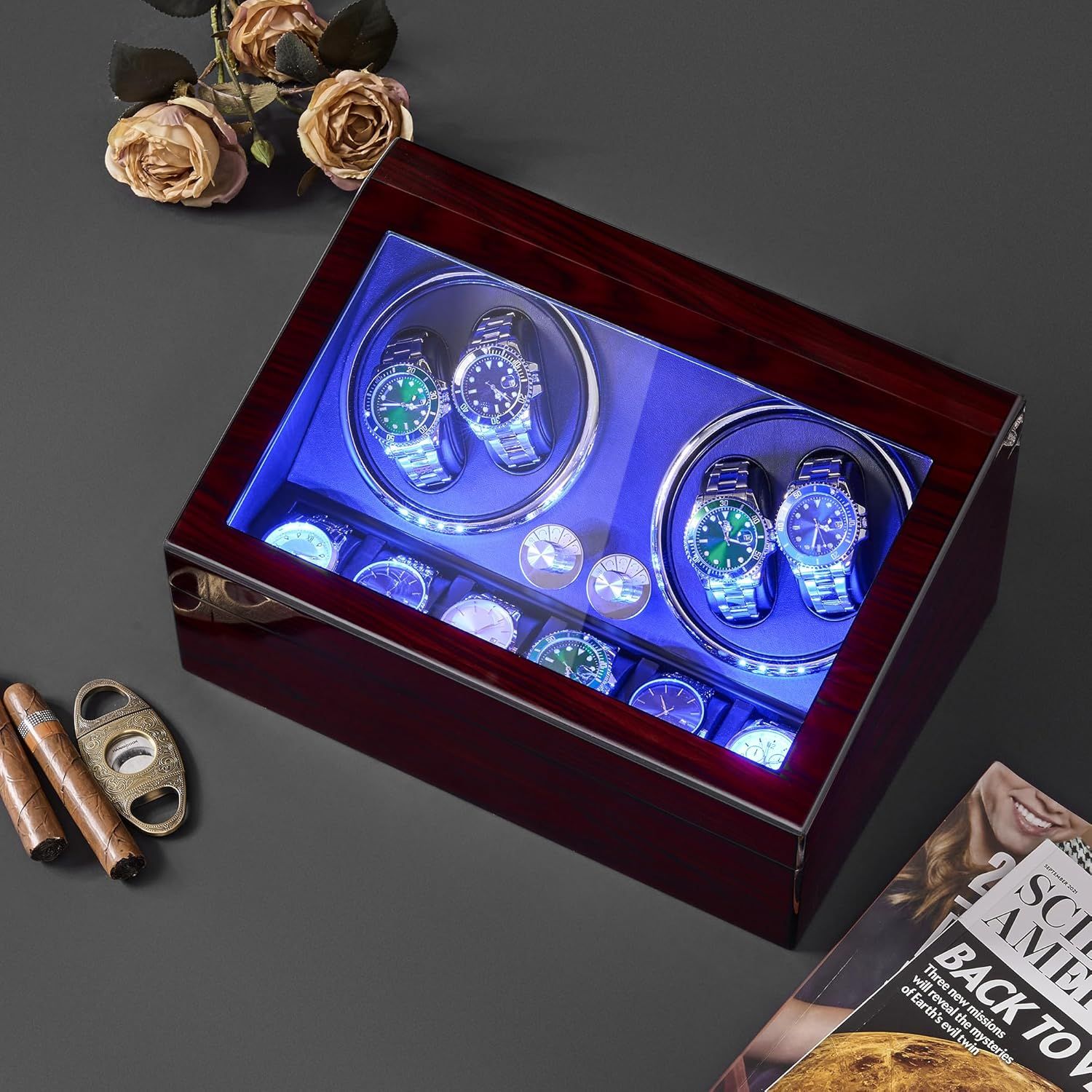Positions the watch winder as a premium gift item through elegant staging with flowers, cigars, and magazine, appealing to gift-givers seeking sophisticated presents.