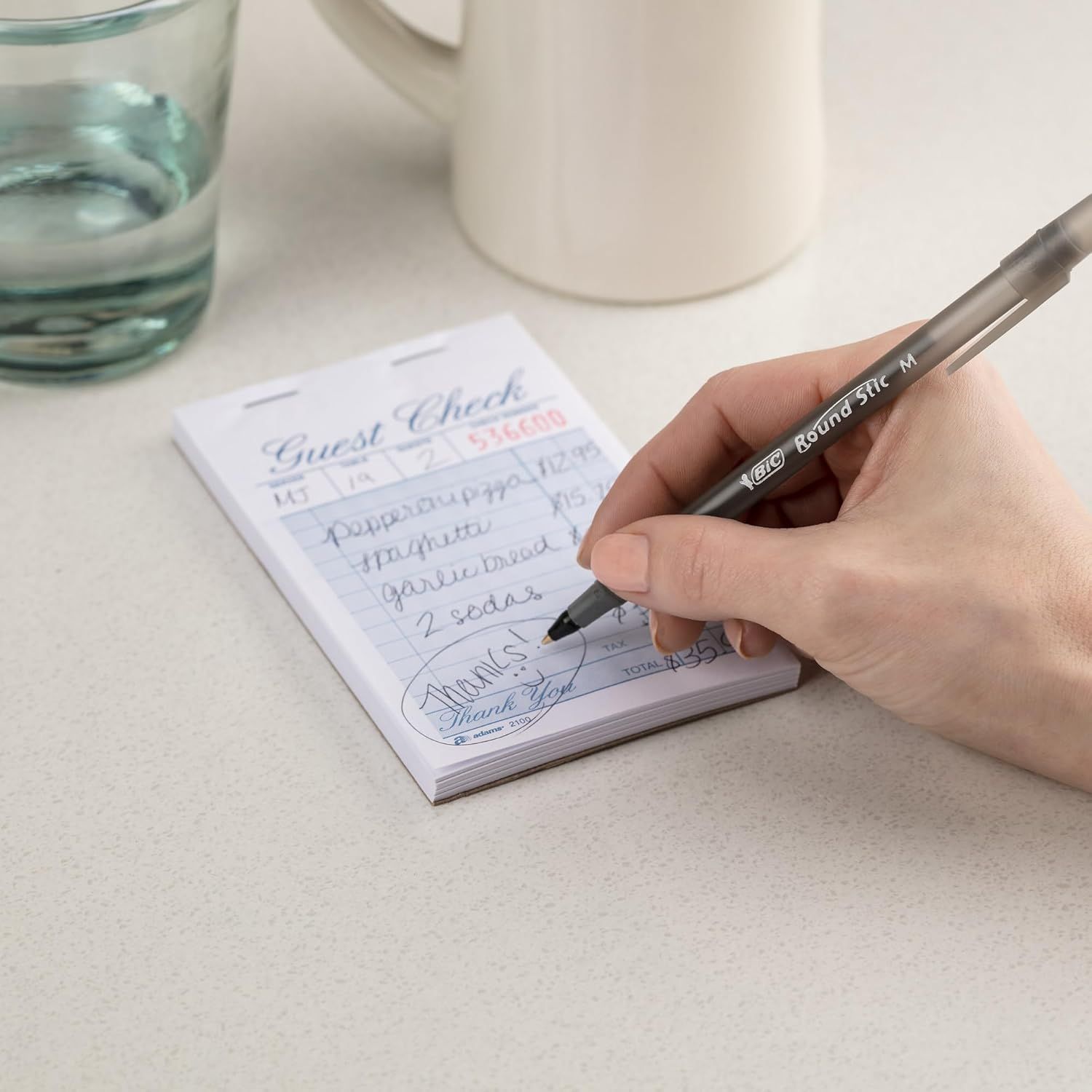 Demonstrates the product being used in an authentic, real-world setting to help shoppers visualize how they would use the guest check notepad in their own restaurant, café, or hospitality business.