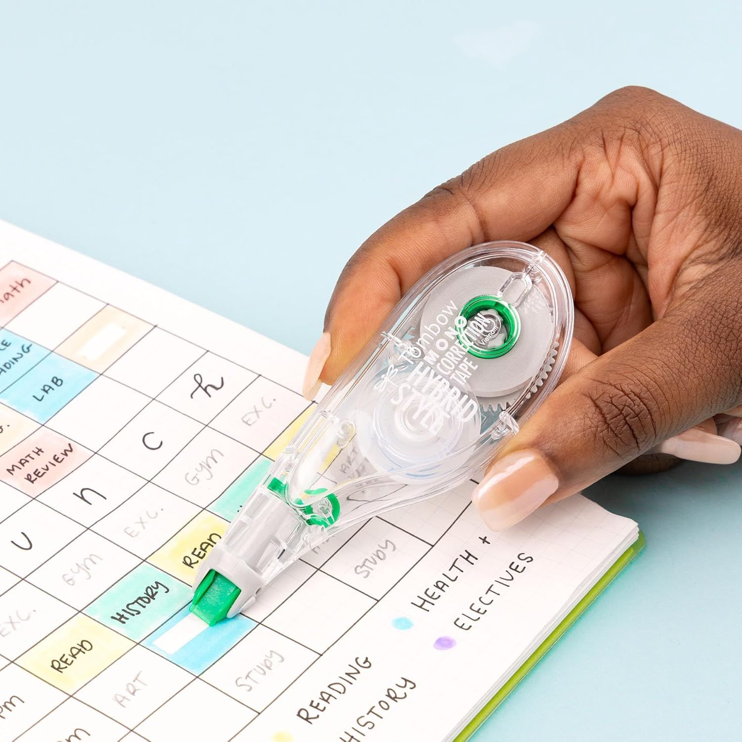 Demonstrates the product being used in a real-world setting (studying/planning) to help shoppers visualize how the correction tape fits into their daily routine.