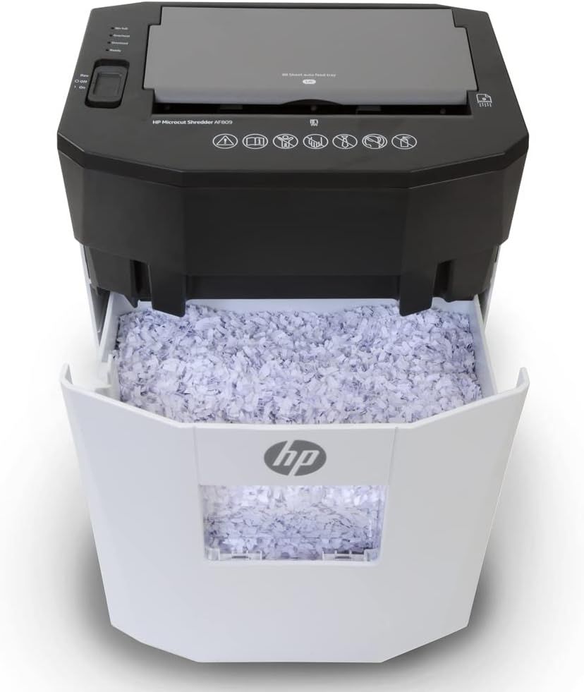 Shows the HP Microcut Shredder with its bin pulled out and filled with shredded paper, demonstrating the product's functionality and bin capacity in a clean, catalog-style presentation.