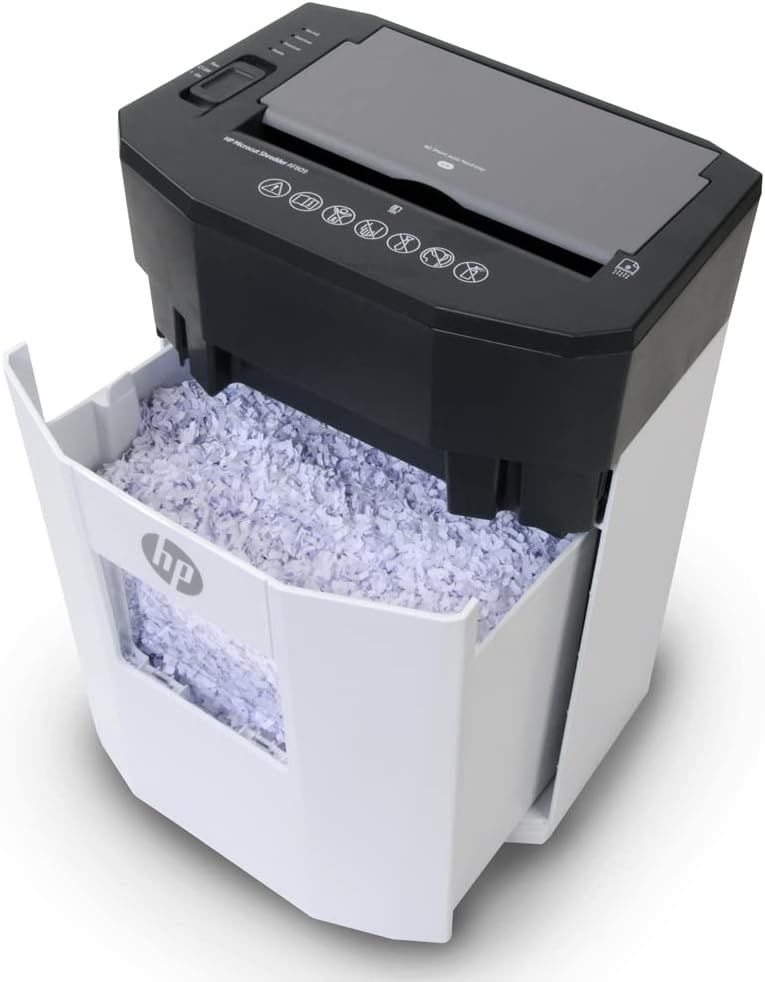Shows the paper shredder with its pull-out waste bin filled with shredded paper, demonstrating the product's functionality and waste collection feature in a clean catalog-style presentation.