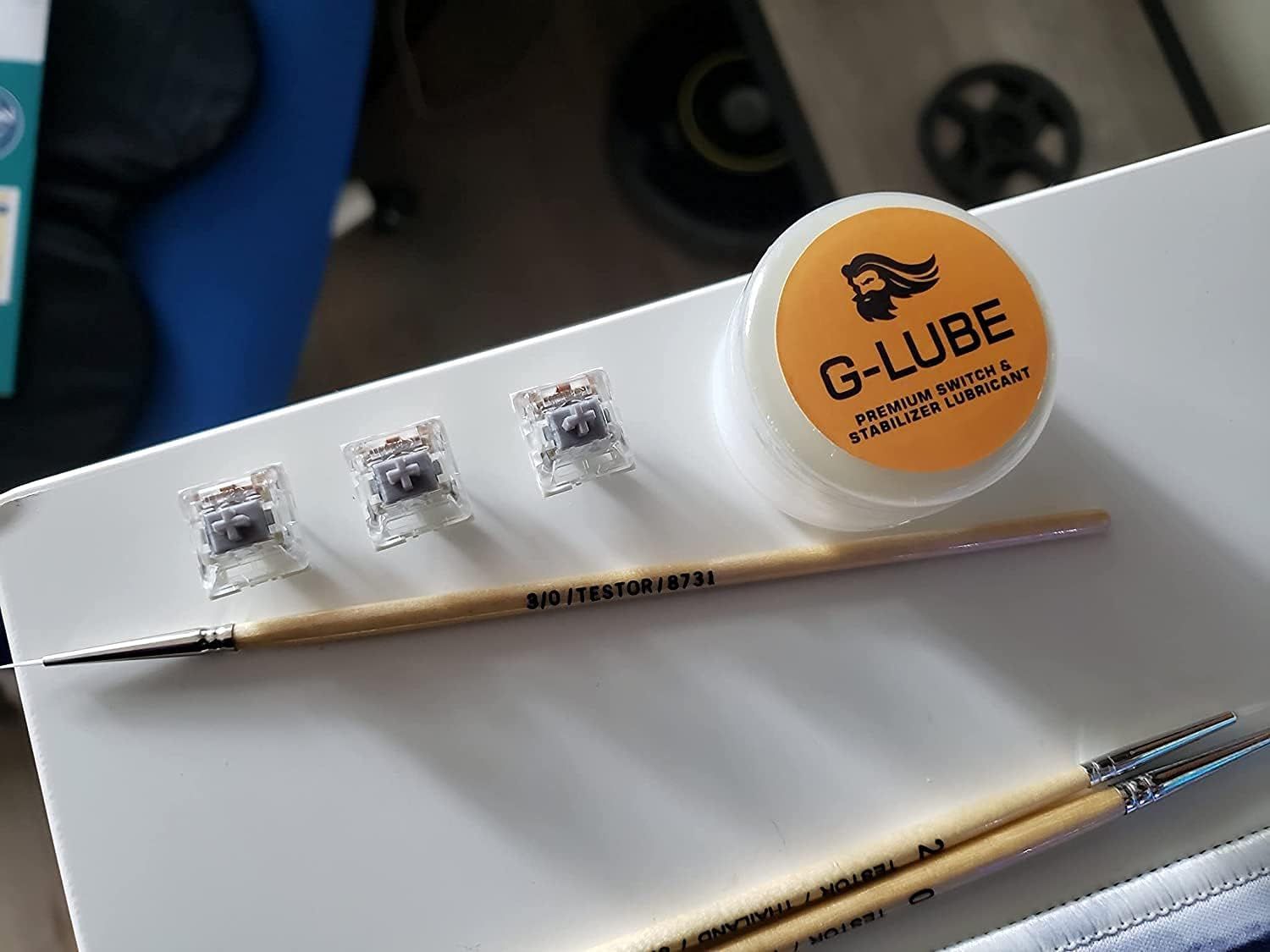 Shows all the items included in the purchase: keyboard switches, lubricant, and application tools, helping shoppers understand they receive everything needed for switch maintenance.