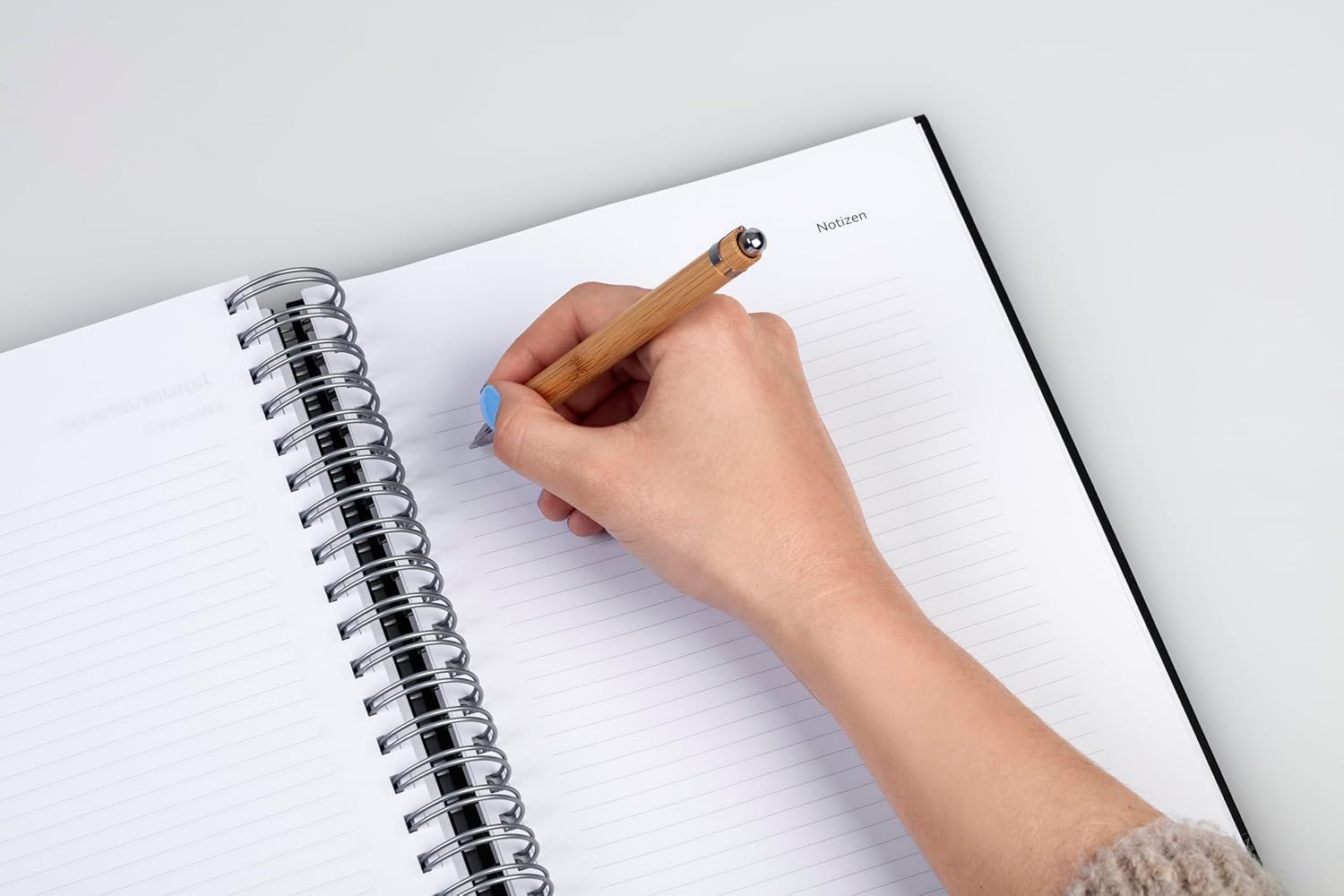 Shows the product being used in a natural, real-world setting to help shoppers visualize how they would use the notebook and pen in their daily life.