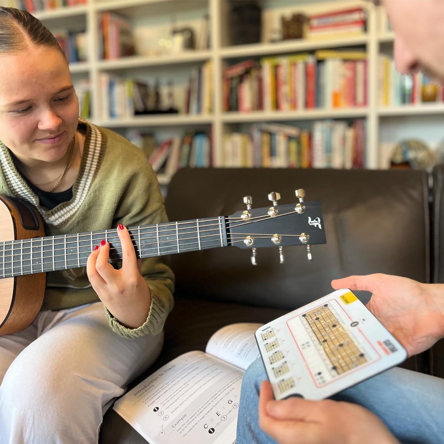 Shows the product being used in a real-world learning context with two people practicing guitar together at home.