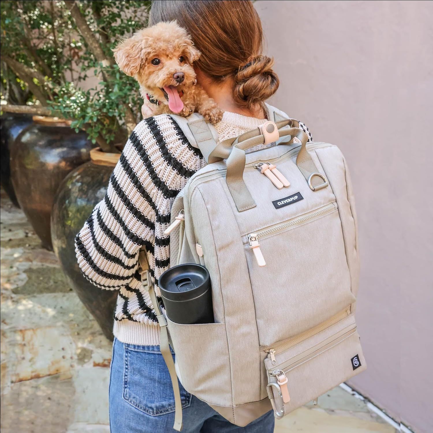 Shows the backpack in a real-world lifestyle context with a dog, demonstrating its use as a pet carrier or travel bag for pet owners.