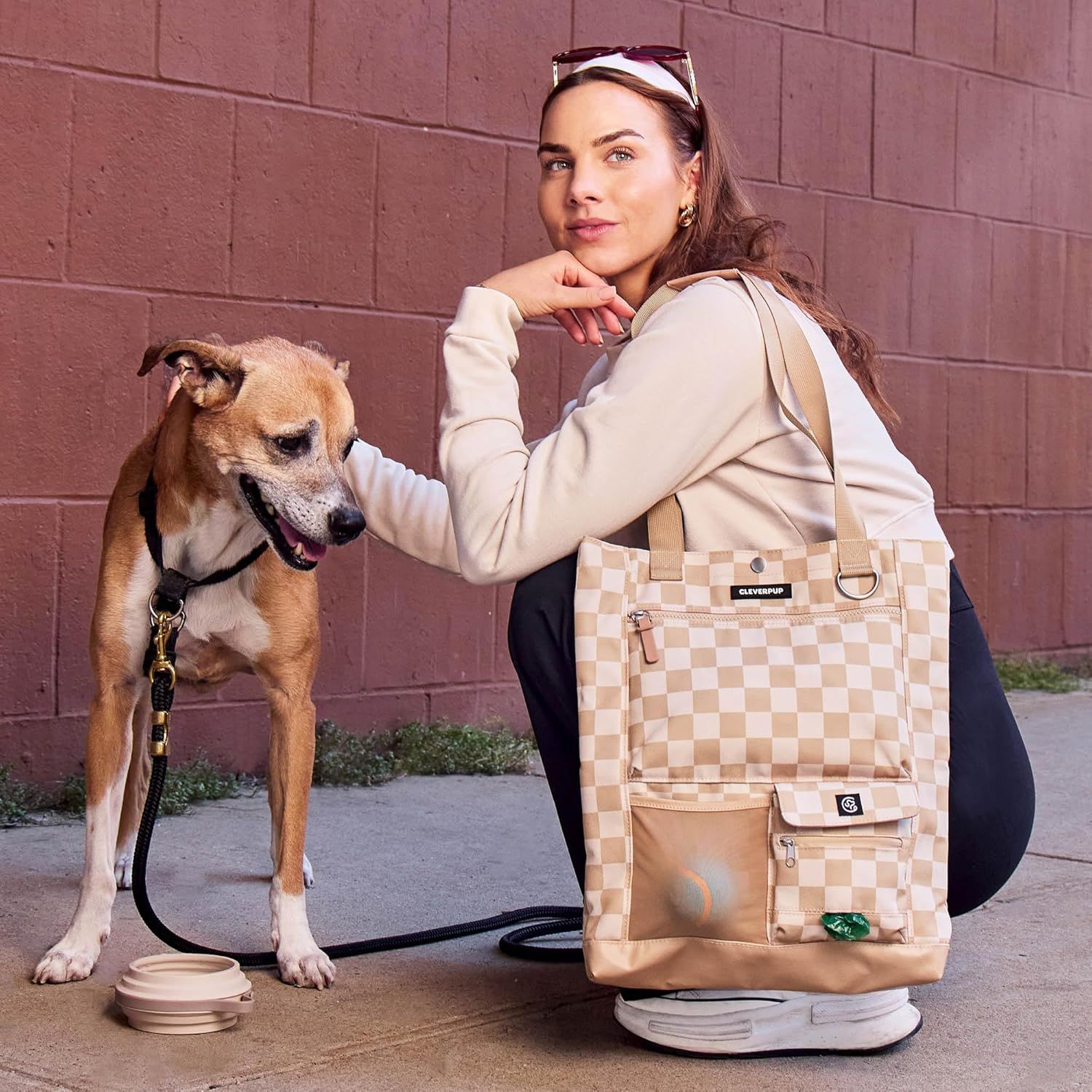 Shows the product in a natural outdoor setting with a person and dog to help shoppers visualize using the tote in everyday life.