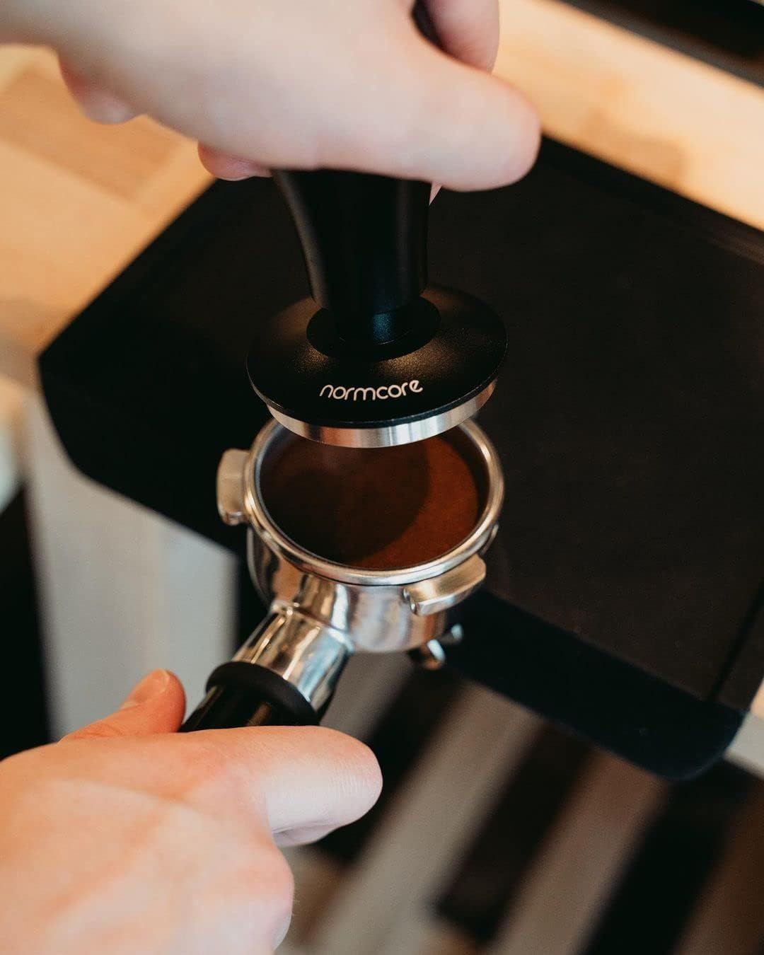 Shows the coffee tamper being used in a real-world espresso preparation setting to help shoppers visualize the product in action.