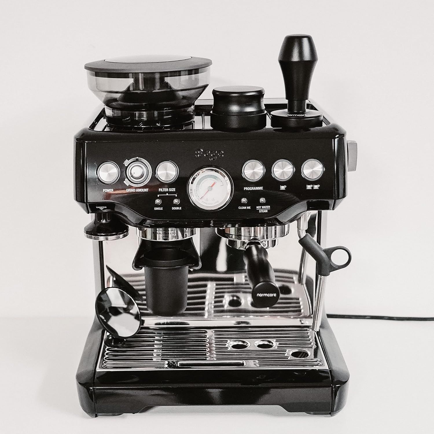 Shows the complete espresso machine with the tamper as part of the overall coffee-making system in a real-world context.