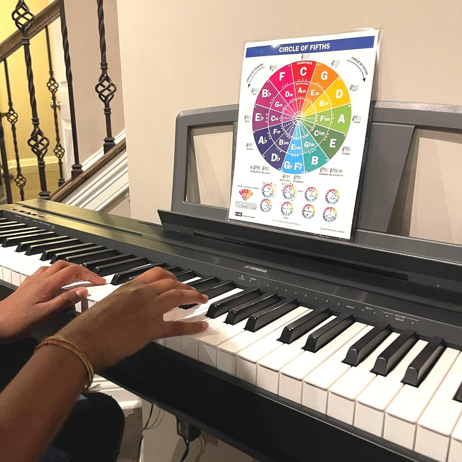 Displays the Circle of Fifths chart being used during actual piano practice, allowing shoppers to see the product in a realistic home music learning environment.