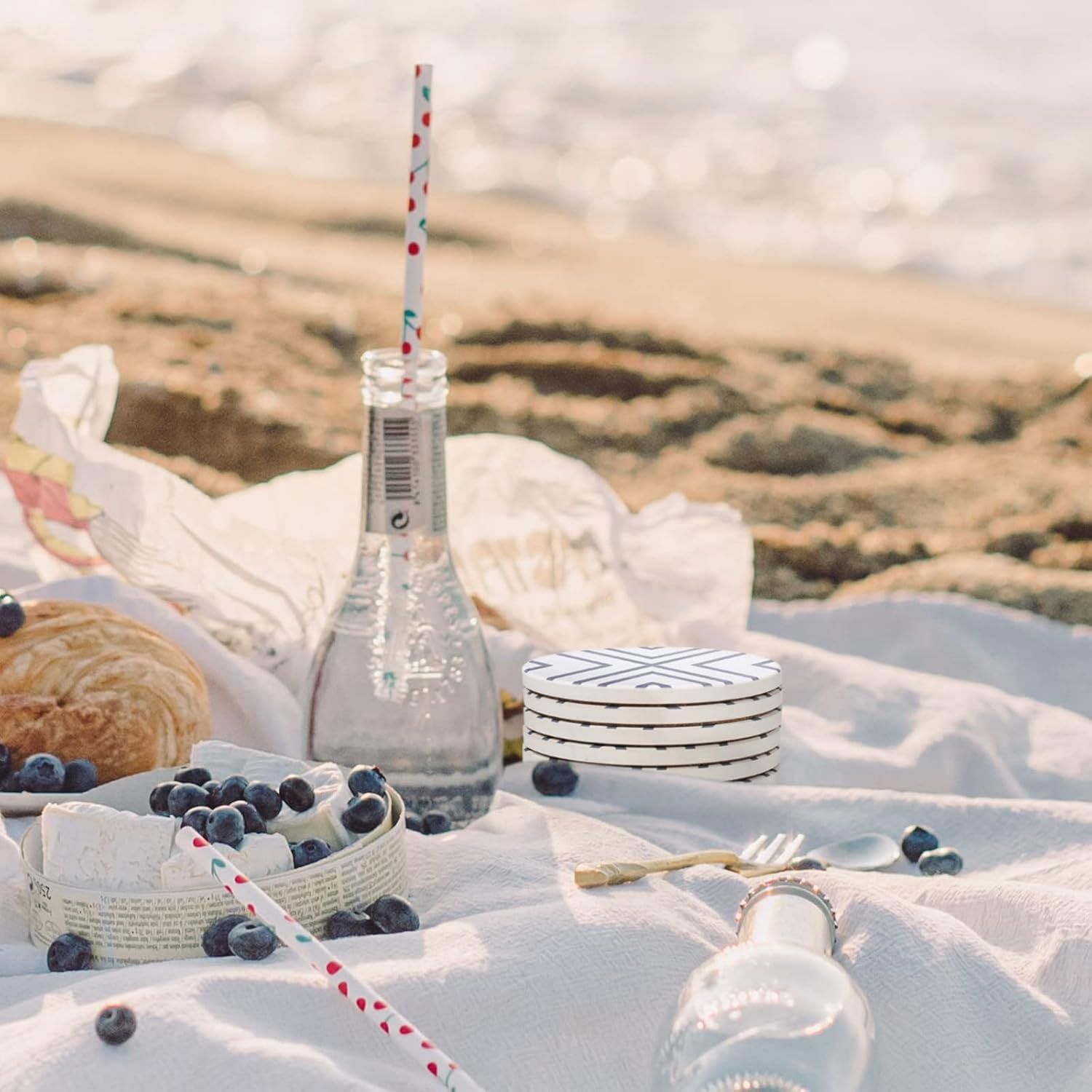 Shows the coasters in an outdoor beach picnic setting to demonstrate portability and suitability for outdoor entertaining.
