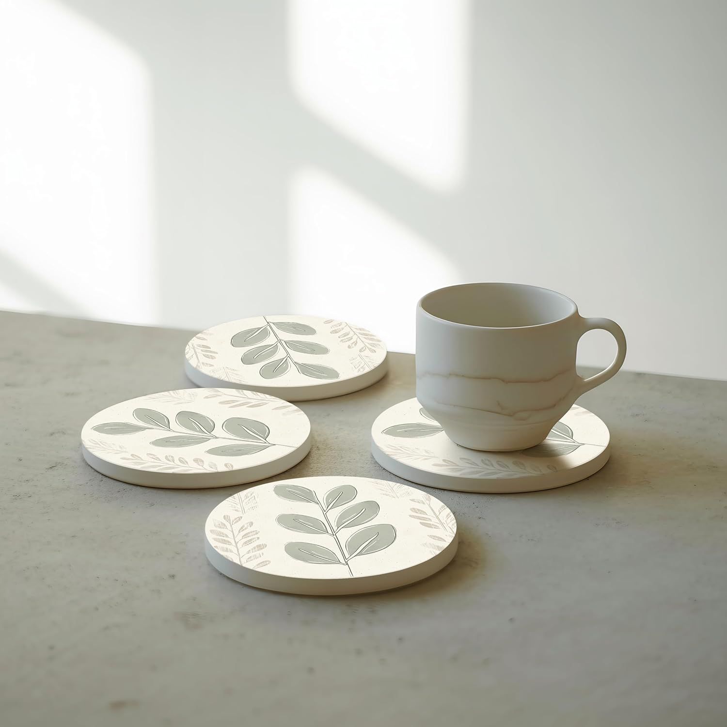 Displays the coasters in a clean, minimalist home environment with a coffee cup to demonstrate everyday use and aesthetic appeal.