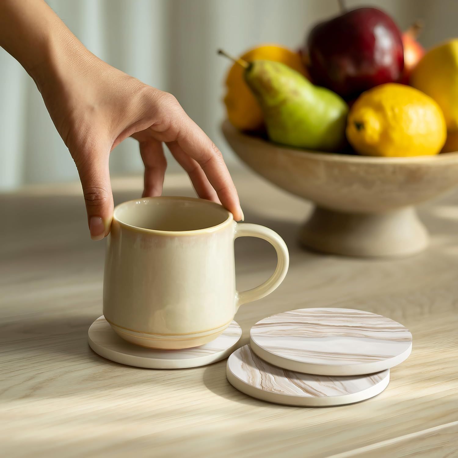 Demonstrates the coasters in everyday kitchen use with a hand reaching for a mug, showing the product in a natural home environment.