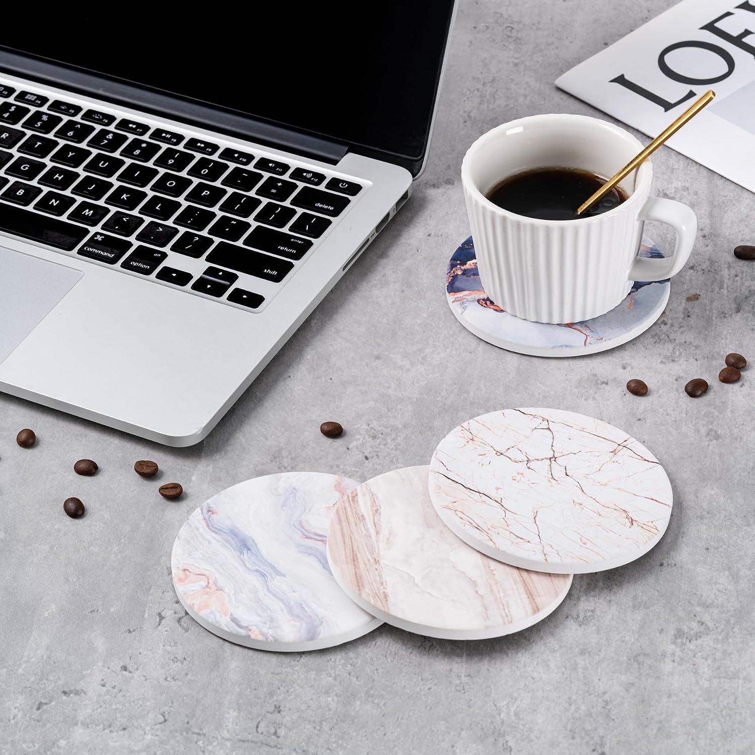 Displays the coasters in a professional workspace setting with a laptop to help shoppers envision using the product at work or home office.